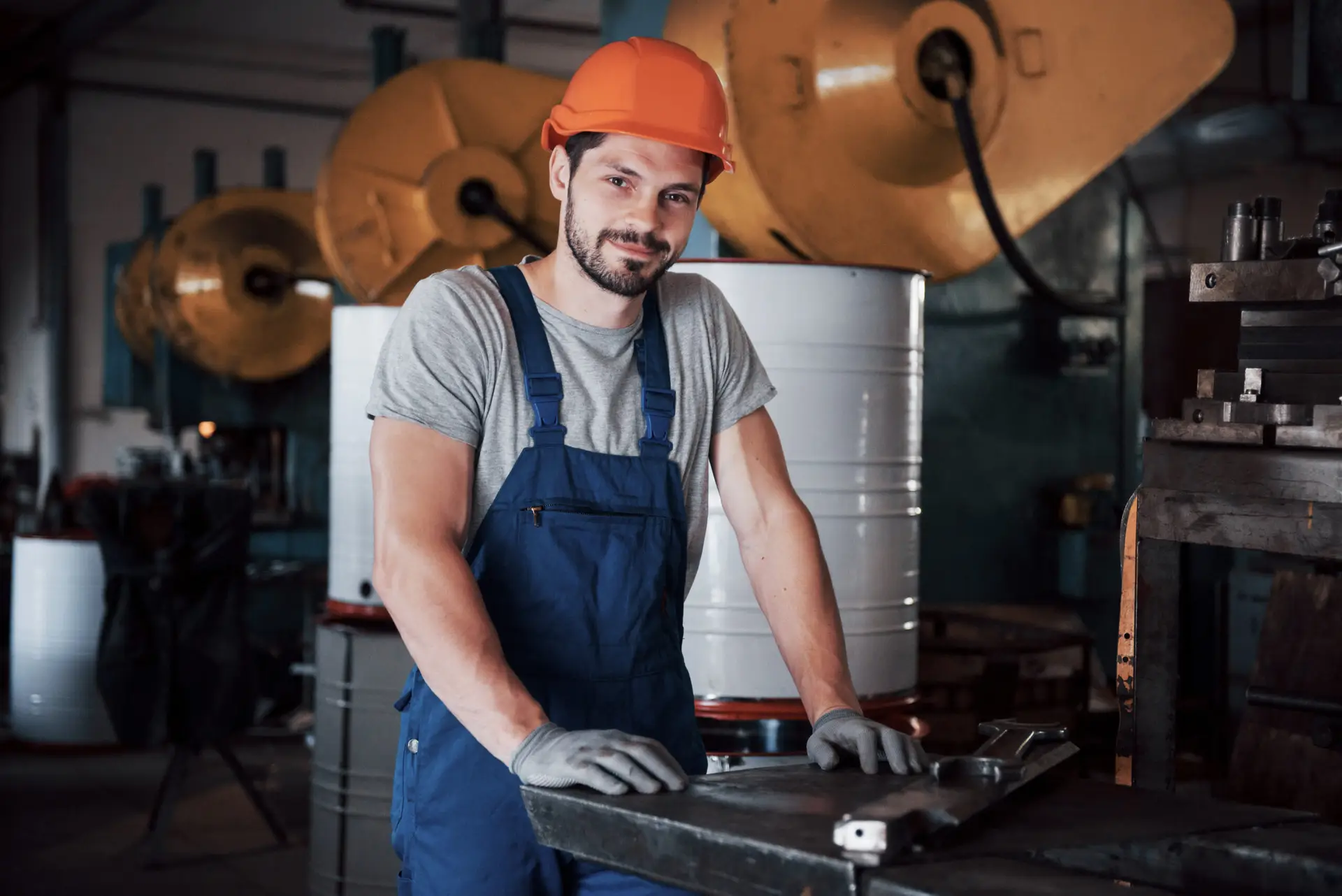 portrait of a young worker in a hard hat at a large metalworking plant. the engineer serves the machines and manufactures parts for gas equipment